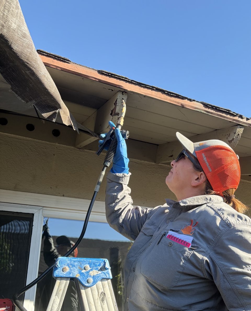 Chris injecting termite treatment into a damaged rafter tail under the eaves